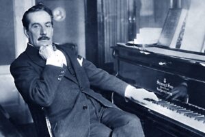 Black and White photograph of Giacomo Puccini sitting at his piano