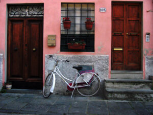 White lady bicycle parked in front of a house in Lucca